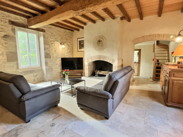 Intérieur d'une maison en pierre avec un salon confortable et une cheminée.