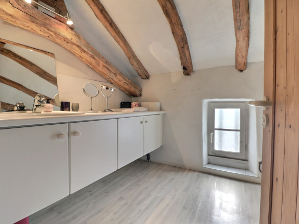 Intérieur d'une maison avec des poutres apparentes et un meuble de salle de bain.