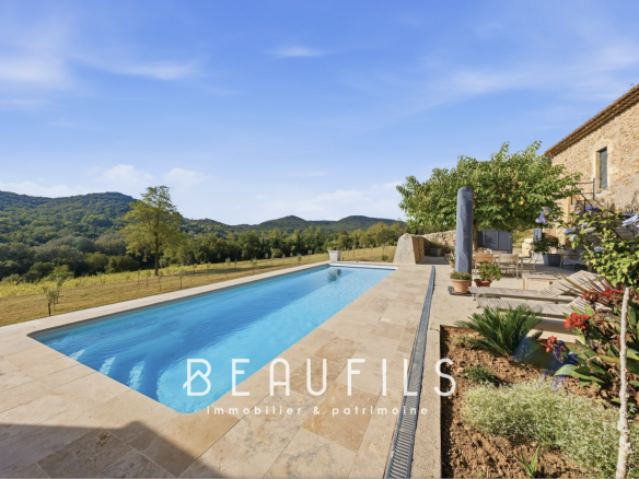 Piscine avec vue sur les collines et mas en pierre dans un domaine de caractère à Orange.