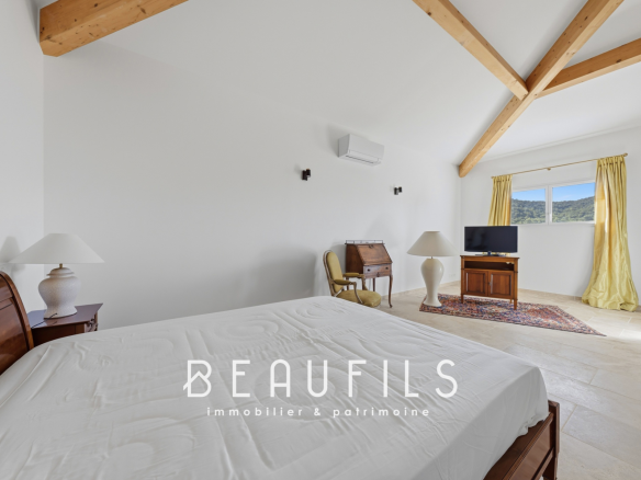 Chambre lumineuse avec lit et vue sur les collines environnantes.