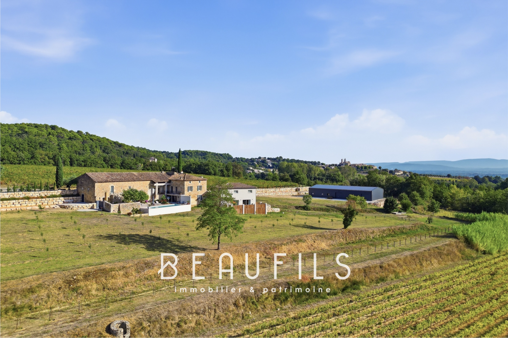 Domaine avec vignoble et mas historique Vue panoramique d'un domaine avec vignoble et mas historique en pierre, entouré de collines.