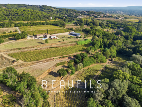 Vue aérienne d'un domaine viticole avec un mas historique et des collines en arrière-plan près d'Orange.