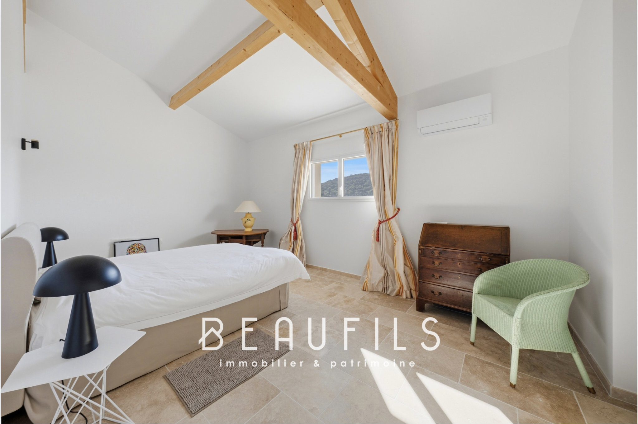 Chambre dans un domaine historique Chambre lumineuse avec plafond à poutres apparentes et mobilier moderne.