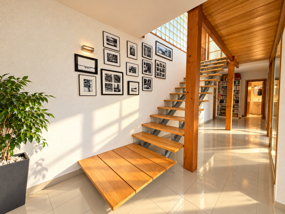 Intérieur d'une maison d'architecte avec un escalier en bois et des murs éclairés par la lumière naturelle.