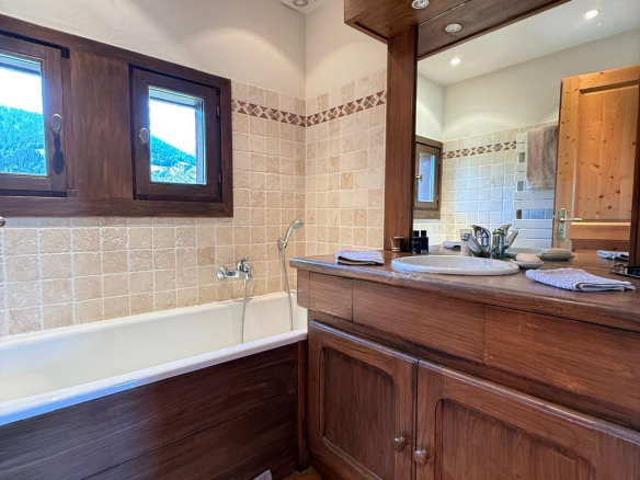Salle de bain d'un chalet avec baignoire et meuble en bois.