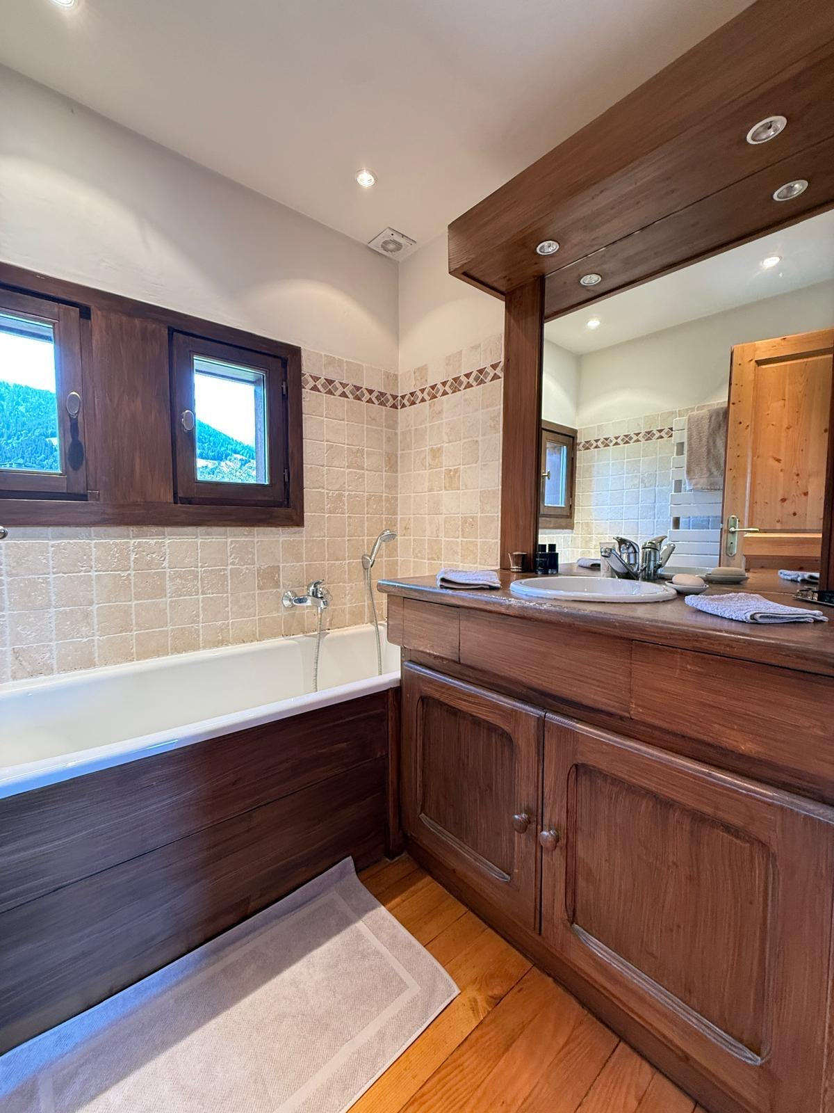 Salle de bain d'un chalet avec baignoire et meuble en bois.