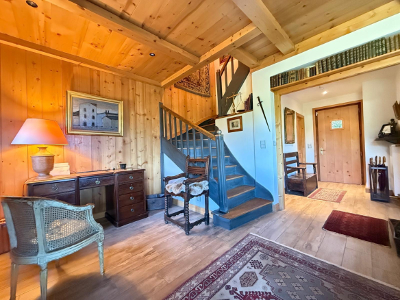 Intérieur d'un chalet en bois avec un escalier et des meubles traditionnels.