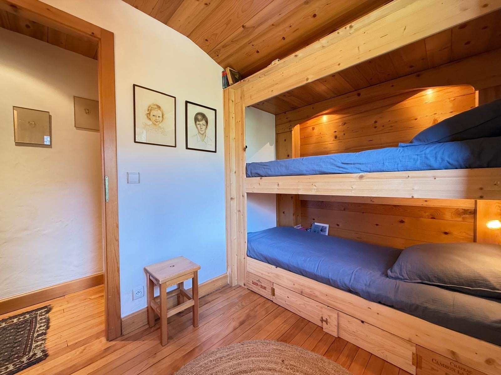 Chambre d'un chalet en bois avec lits superposés et décoration chaleureuse.
