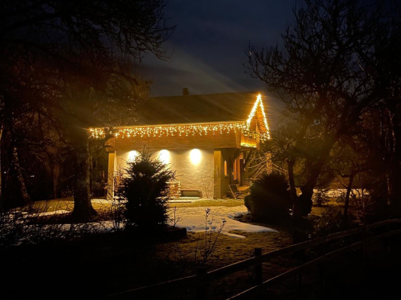 Chalet illuminé la nuit avec des décorations lumineuses, entouré d'arbres et de neige.