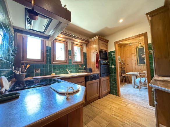 Cuisine d'un chalet en bois avec carrelage et fenêtres donnant sur l'extérieur.