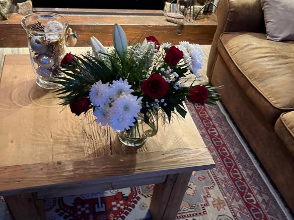 Intérieur d'un chalet avec un bouquet de fleurs sur une table en bois et un feu de cheminée.