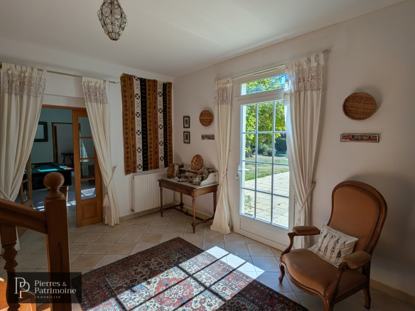 Intérieur d'une maison de caractère avec un salon lumineux et un accès à l'extérieur.