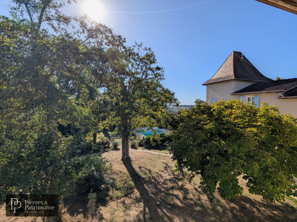 Vue dégagée sur un parc arboré avec une maison de caractère à Nérac.
