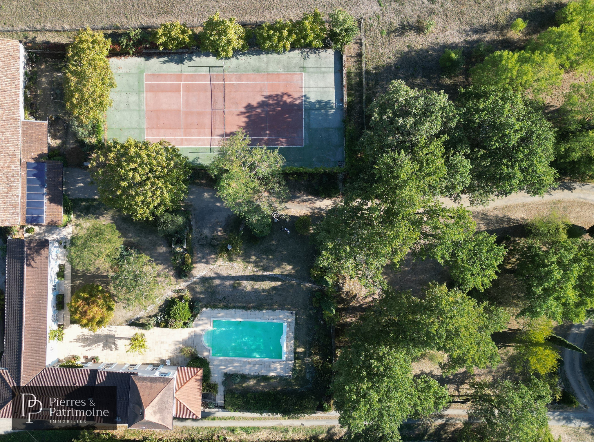 Propriété avec piscine et terrain de tennis à Nérac Vue aérienne d'une propriété avec piscine et terrain de tennis, entourée d'arbres.