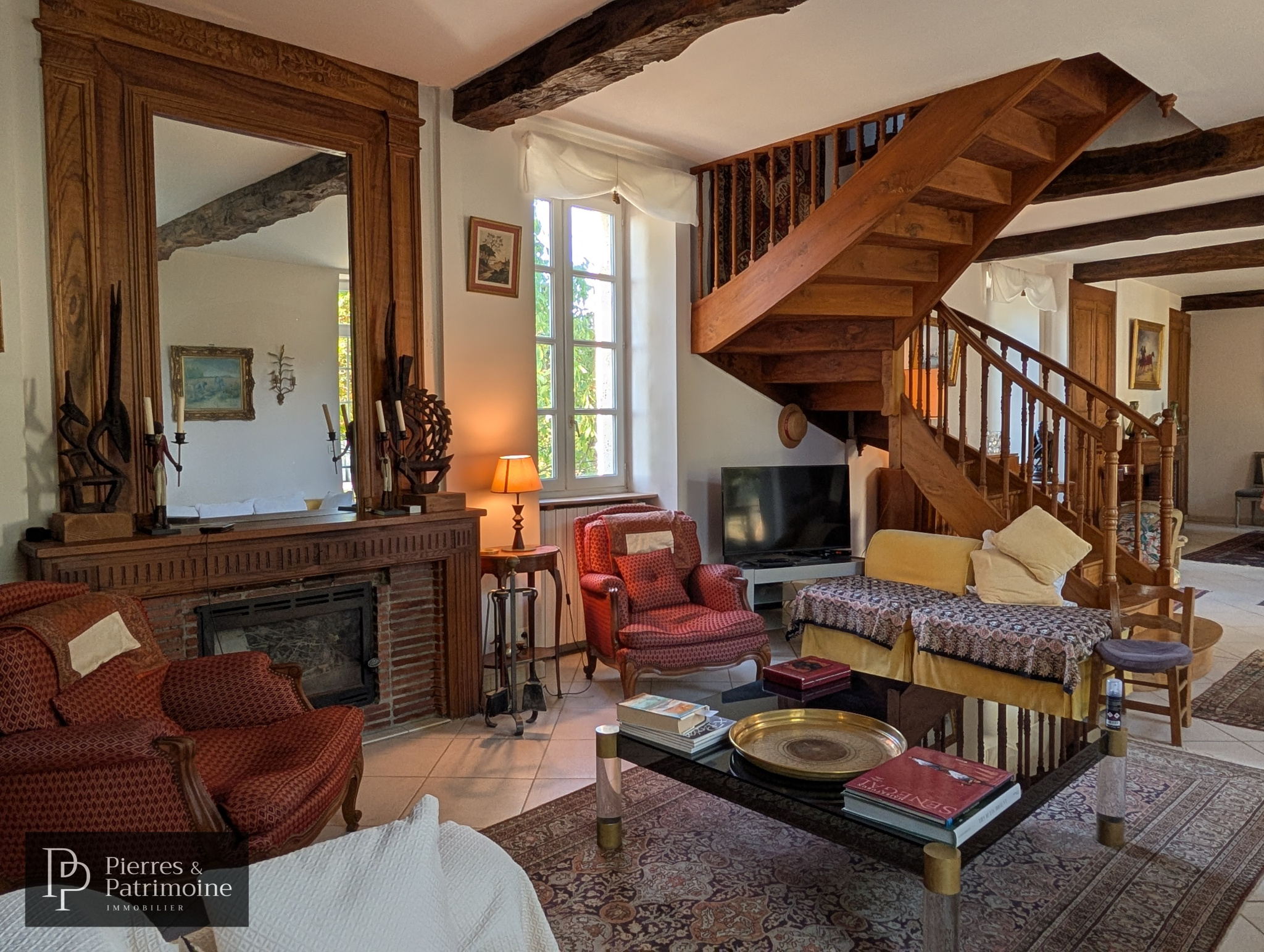 Salon d’une propriété à Nérac Intérieur d'une maison de caractère à Nérac, salon avec cheminée et escalier en bois.