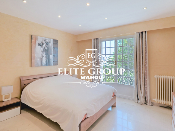 Chambre d'une villa bourgeoise à Nice avec lit double et fenêtre donnant sur l'extérieur.