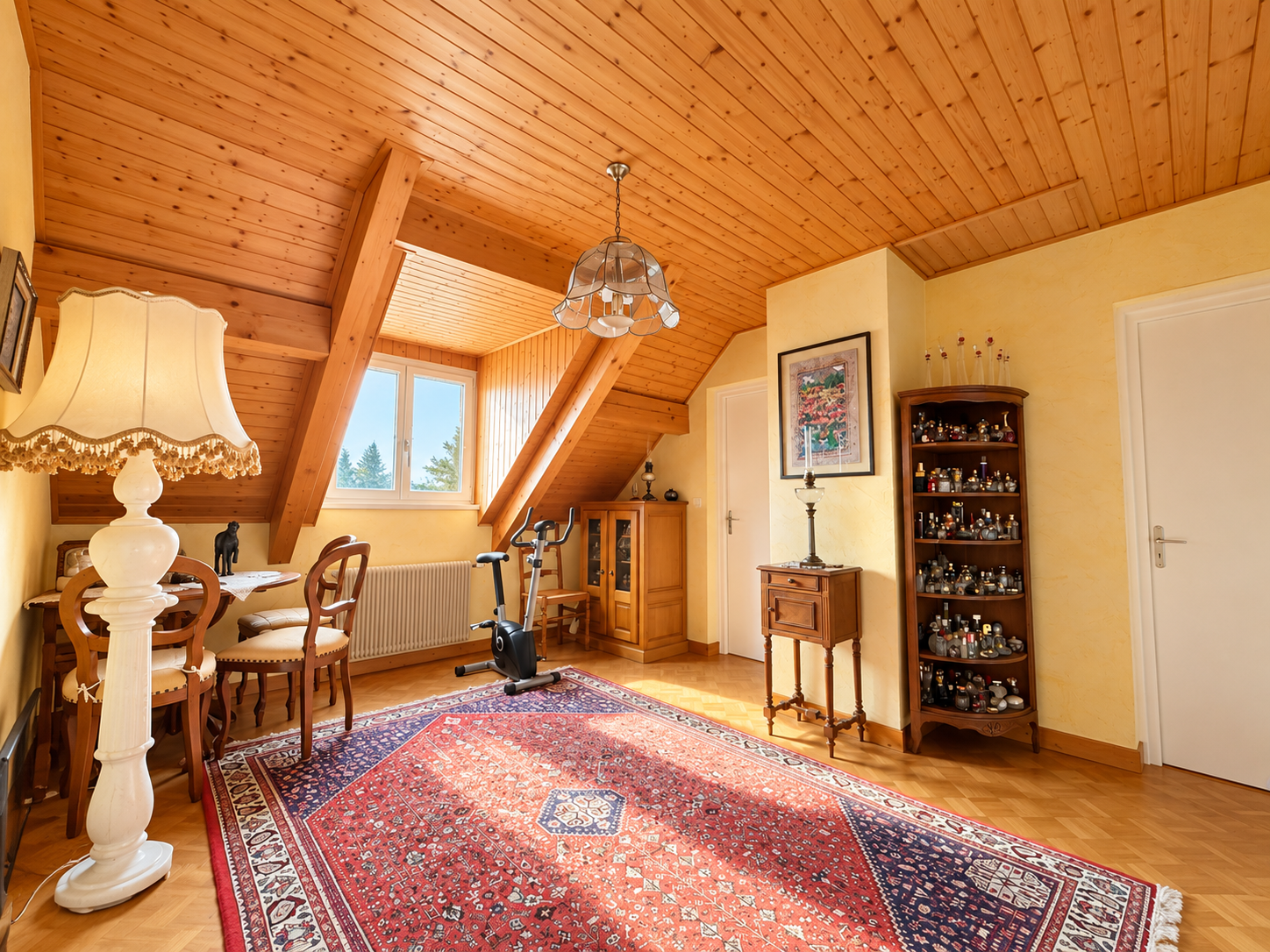 Intérieur d'une maison avec un plafond en bois, un tapis et des meubles, éclairé par une fenêtre.