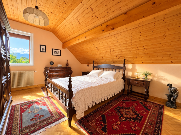 Chambre à coucher avec un lit en bois, tapis et fenêtres, dans une maison à Saint-Jean-de-Gonville.