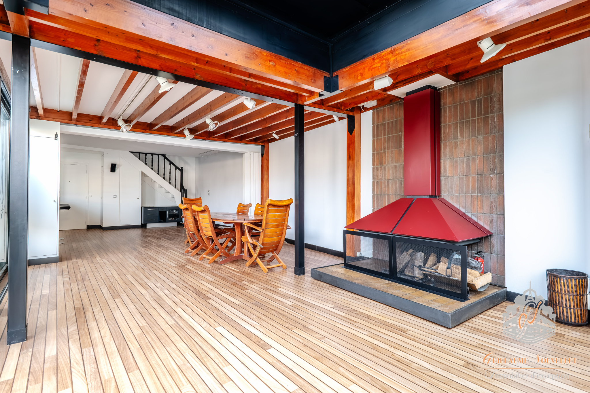 Duplex d’exception à Paris Intérieur d'un duplex avec poutres apparentes et cheminée, salle à manger en bois.
