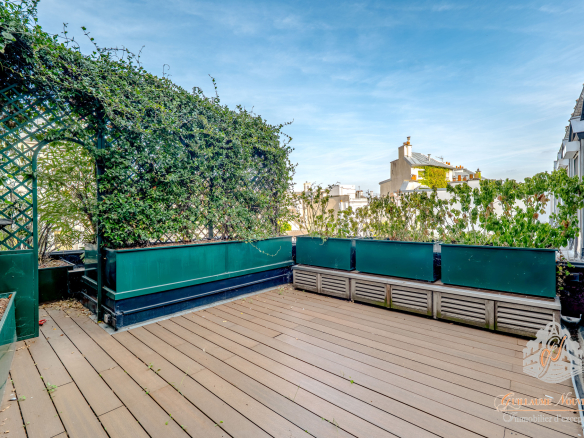 Terrasse privative d'un duplex à Paris, entourée de verdure et d'un ciel dégagé.
