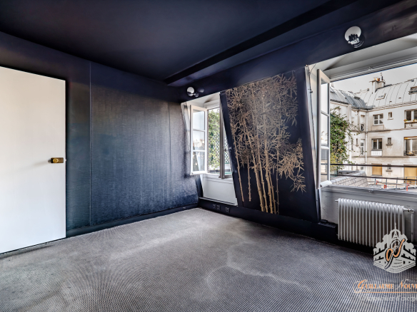 Intérieur d'un duplex avec murs sombres et fenêtres ouvertes sur une vue extérieure à Paris.