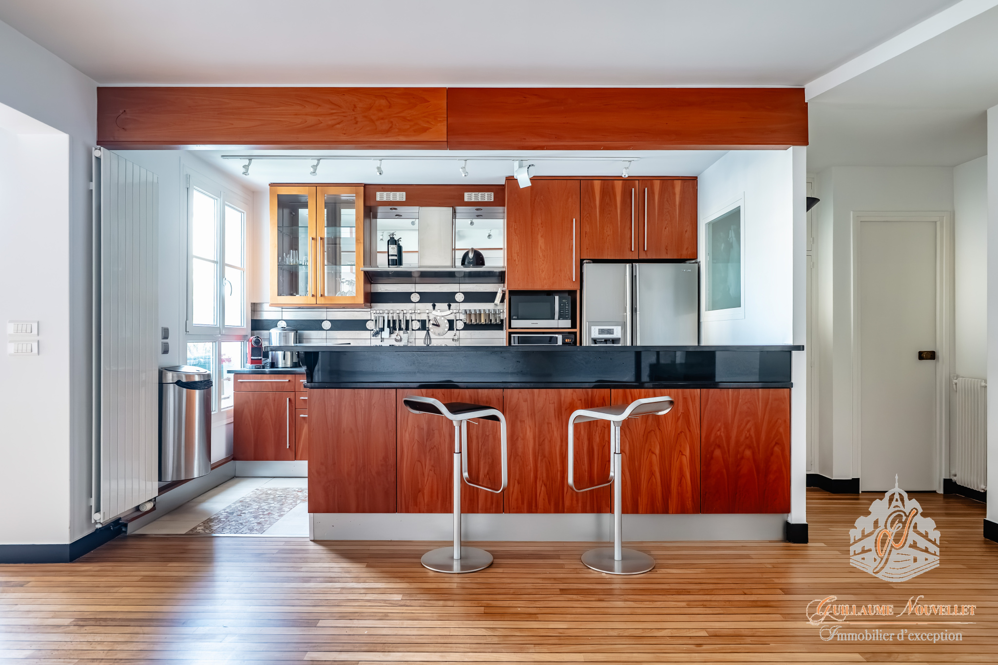 Cuisine d’un duplex d’exception à Paris Cuisine moderne dans un duplex avec comptoir et bar, parquet en bois.