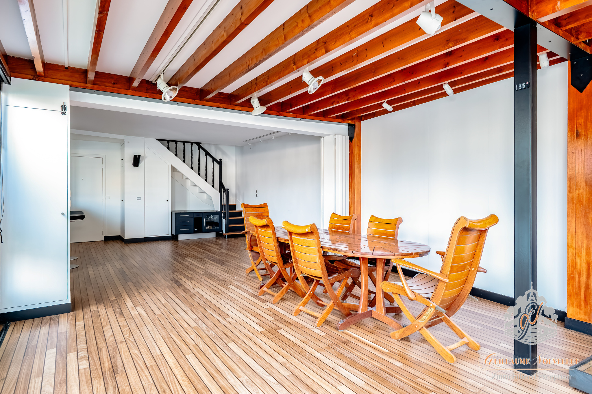 Intérieur d’un duplex à Paris Intérieur d'un duplex avec table en bois et chaises, poutres apparentes, et escalier.