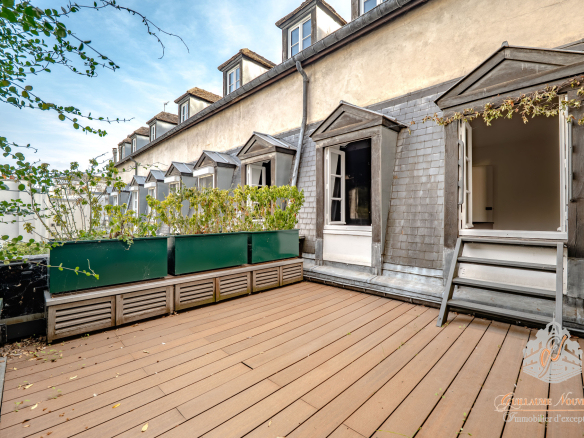 Terrasse d'un duplex avec des structures en bois et des plantes, vue sur un immeuble parisien.