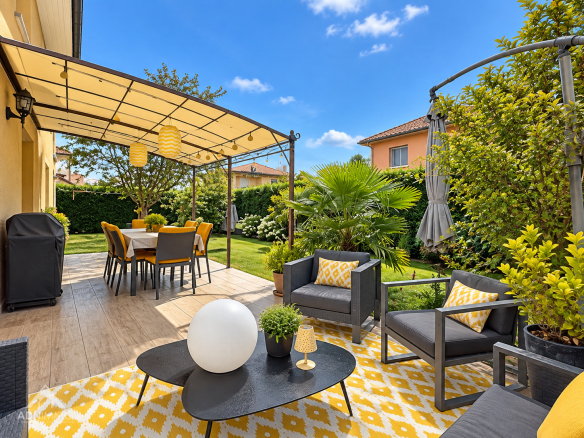 Terrasse aménagée avec salon de jardin et parasol, entourée de verdure, à Saint-Genis-Pouilly.
