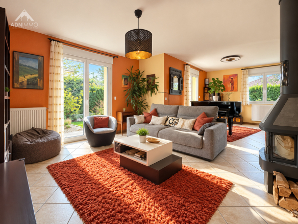 Salon lumineux d'une maison avec canapé, fauteuils et cheminée, décoré de manière conviviale.
