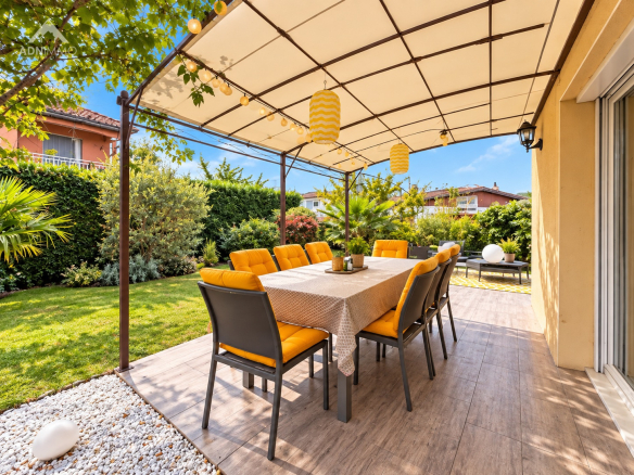 Terrasse ensoleillée avec table et chaises dans un jardin verdoyant à Saint-Genis-Pouilly.