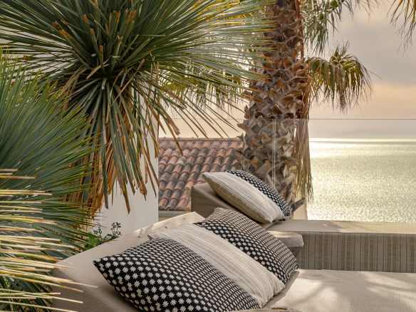 Terrace of a villa with sea view, plants and decorative cushions.
