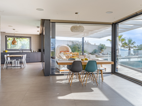 Modern interior of a villa with sea views, bright dining room and open kitchen.