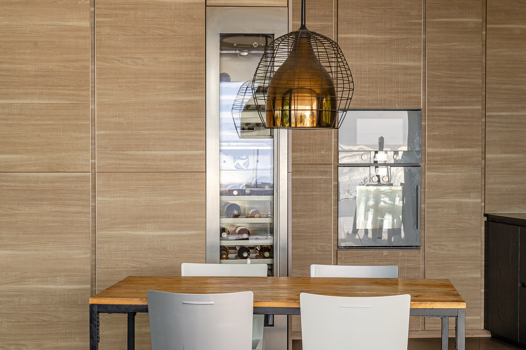 Contemporary cuisine Modern kitchen interior with wooden table and white chairs, designer lighting.