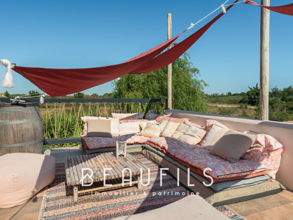 Terrace of a Mediterranean villa with cushions and sails, surrounded by nature.