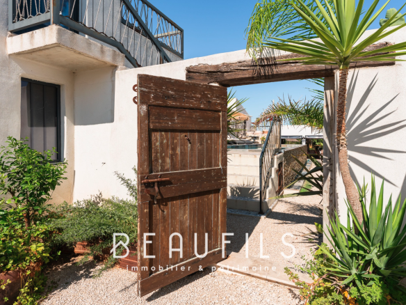 Entrance to a Mediterranean villa with a wooden door and plants, Saintes Maries de la Mer.