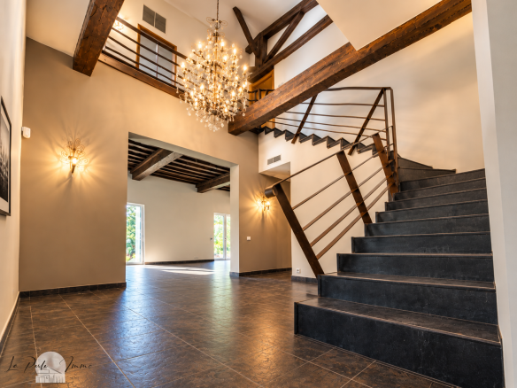 Interior of a renovated former wine cellar with a modern staircase and a chandelier, Perpignan.
