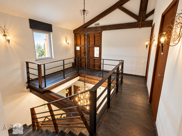 Interior of a renovated old wine cellar with a wooden staircase and balcony, modern lighting.