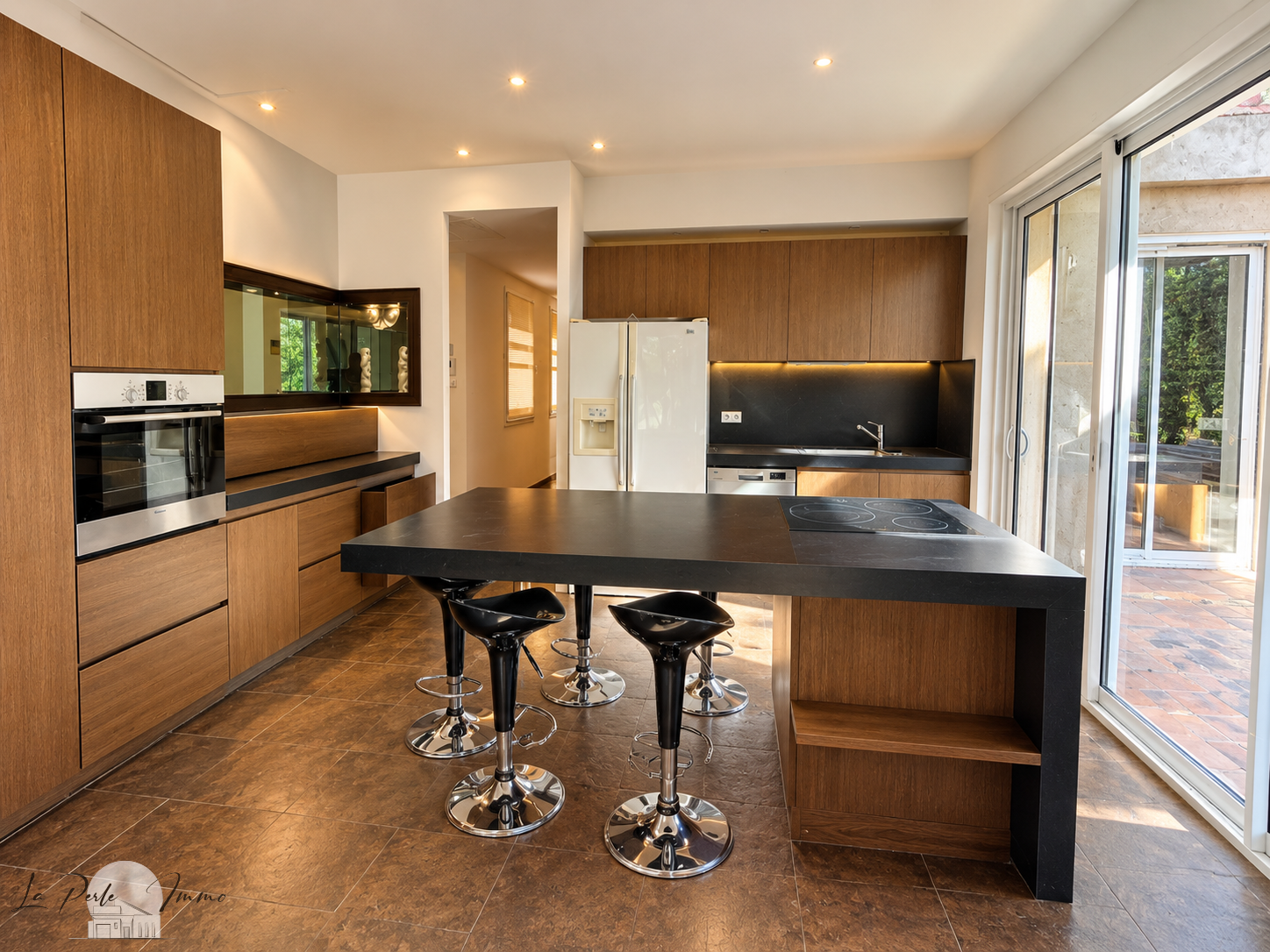 Contemporary cuisine in a former wine cellar Modern kitchen with wooden furniture and black worktop, open to the outside.