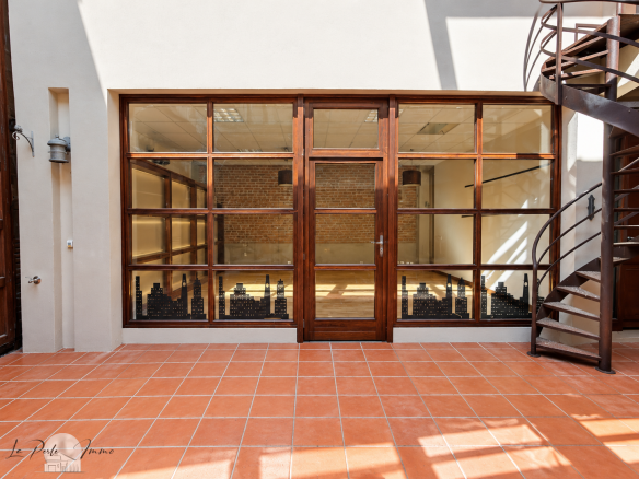 Interior of a renovated old wine cellar with brick walls and a large wooden window.