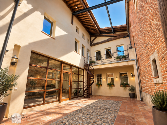 Interior of a renovated former wine cellar with a paved courtyard and brick walls, in Perpignan.