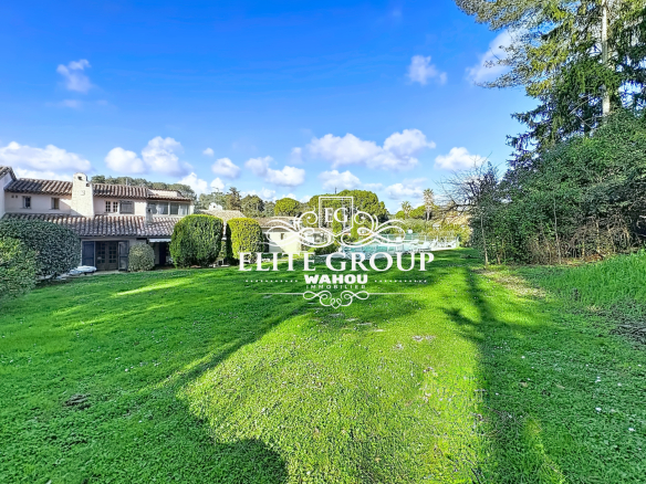 View of a green garden with a Provençal villa in Mougins, under a blue sky.