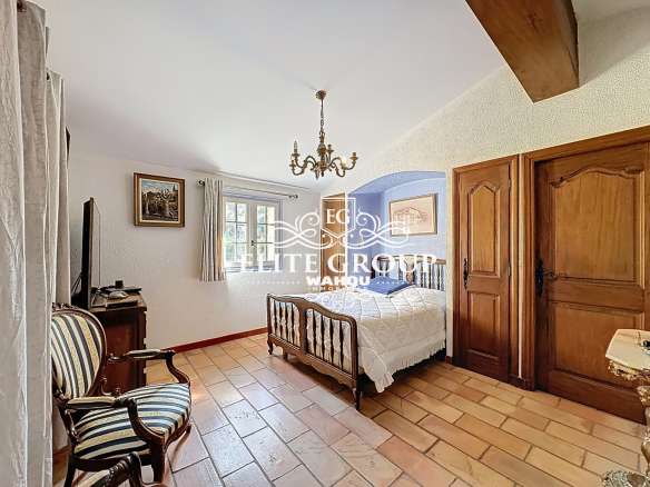 Bedroom in a Provençal villa in Mougins with wooden furniture and tiled floor.