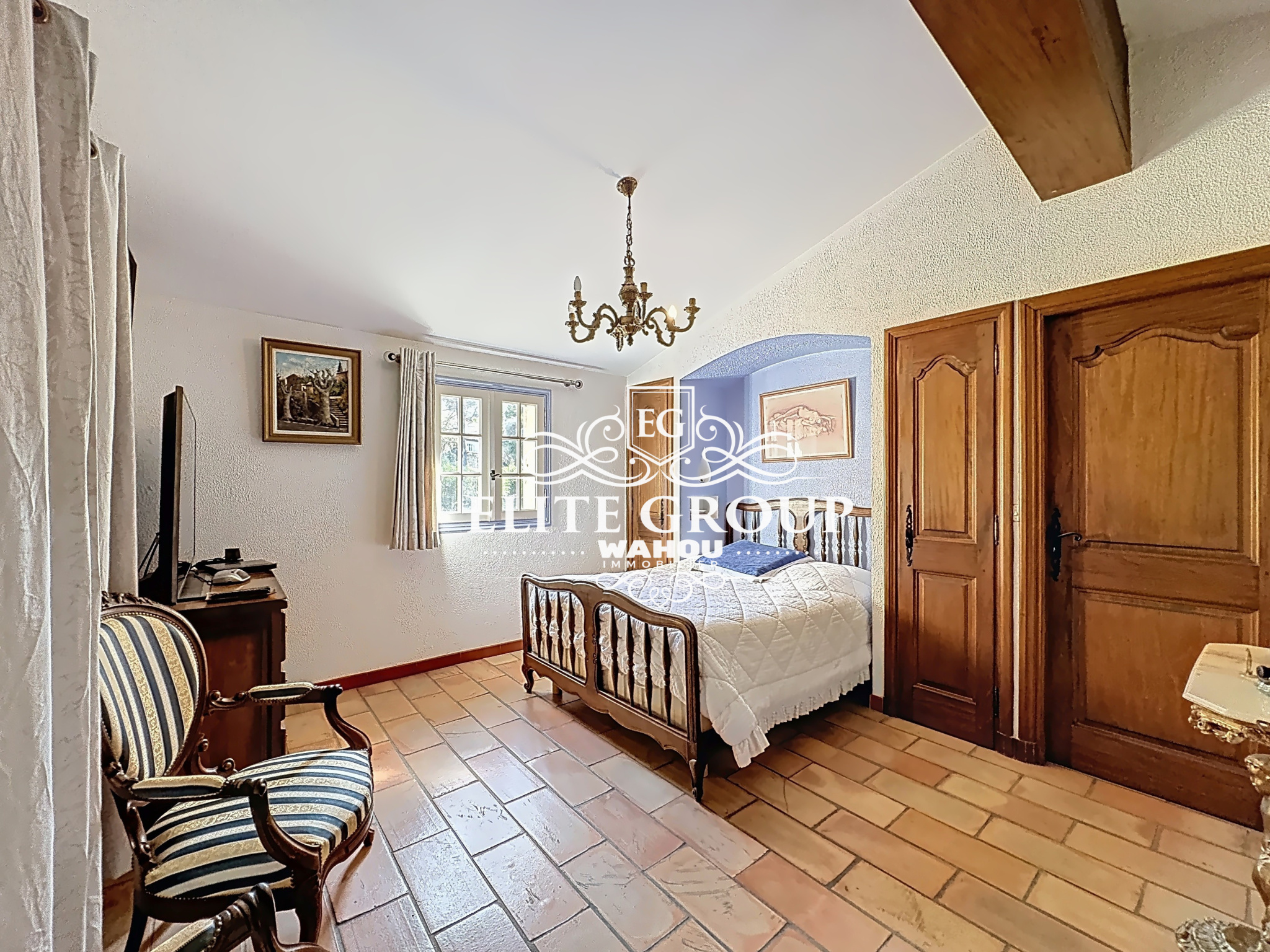 Bedroom in a Provençal villa in Mougins with wooden furniture and tiled floor.