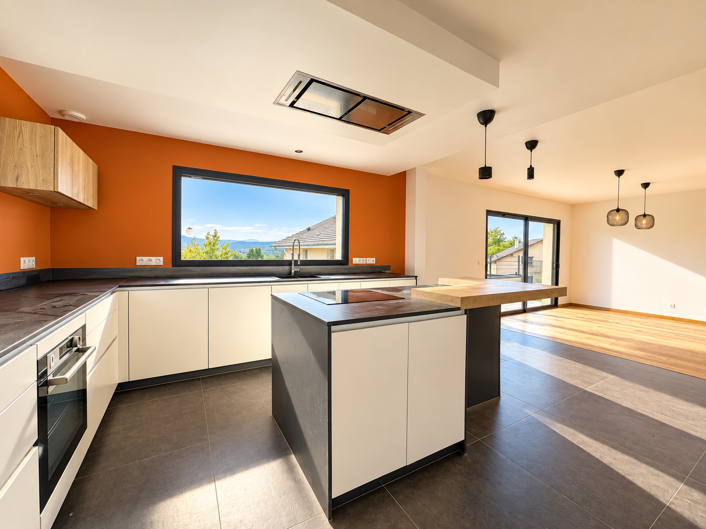 Cuisine moderne à Challex Cuisine moderne avec îlot central et fenêtres offrant une vue sur l'extérieur.
