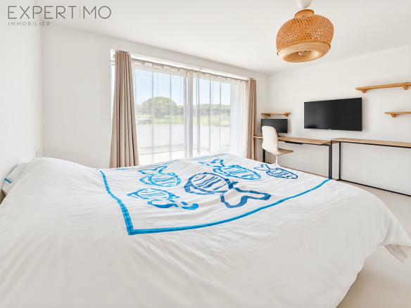 Bright room with a white and blue bed, desk and window overlooking the Brest harbor.