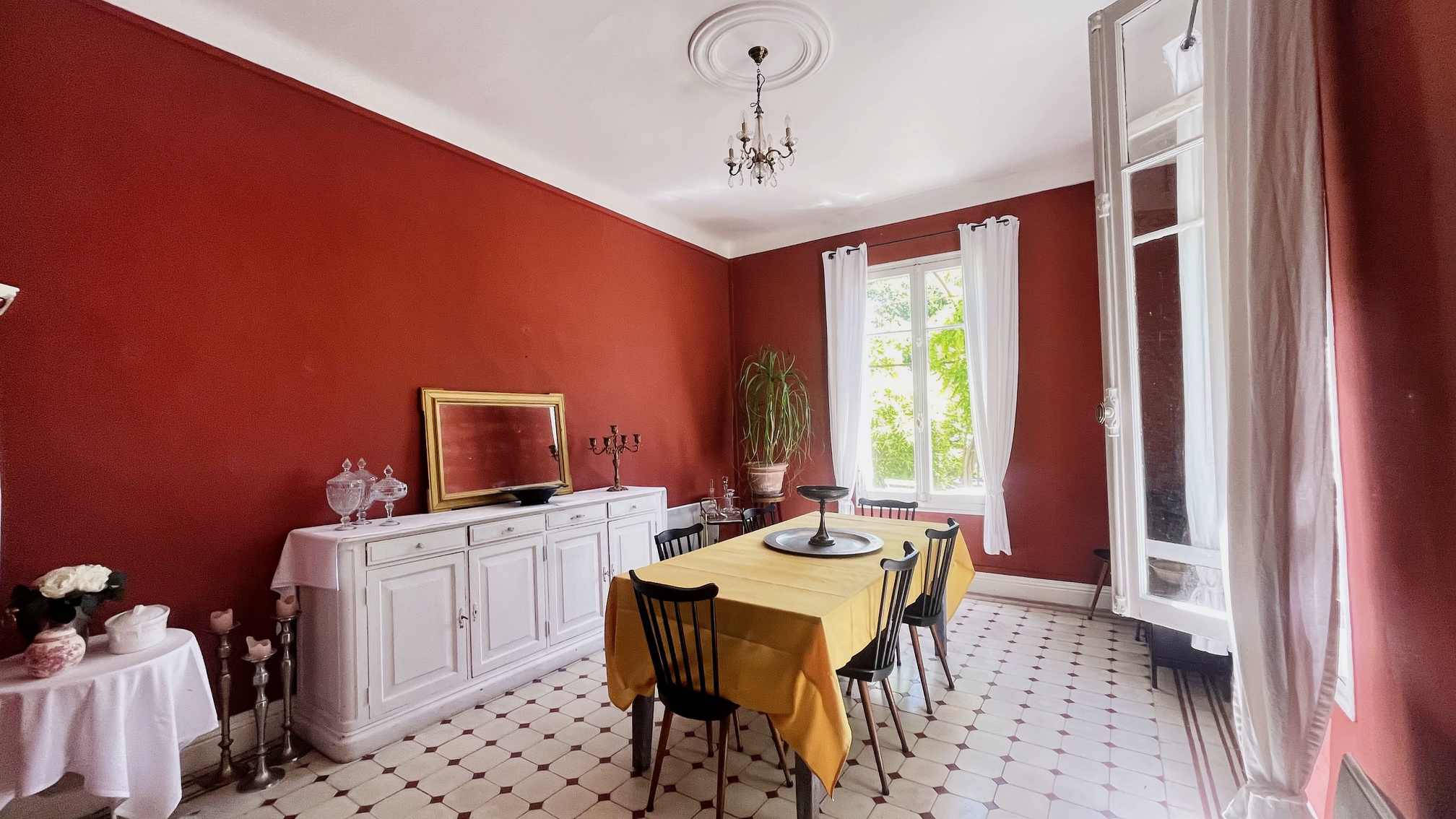 Interior of a dining room with red walls and a table for six people, L'Isle-sur-la-Sorgue.