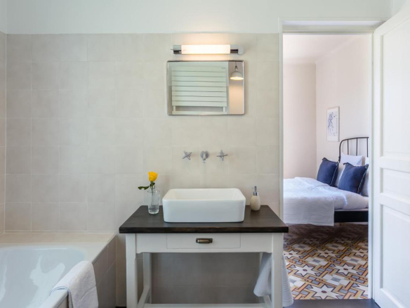 Modern bathroom with bathtub and sink, overlooking a bedroom