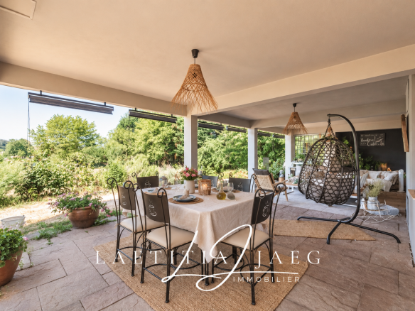 Terrasse d'une propriété atypique à Boofzheim avec table et chaises, entourée de verdure.