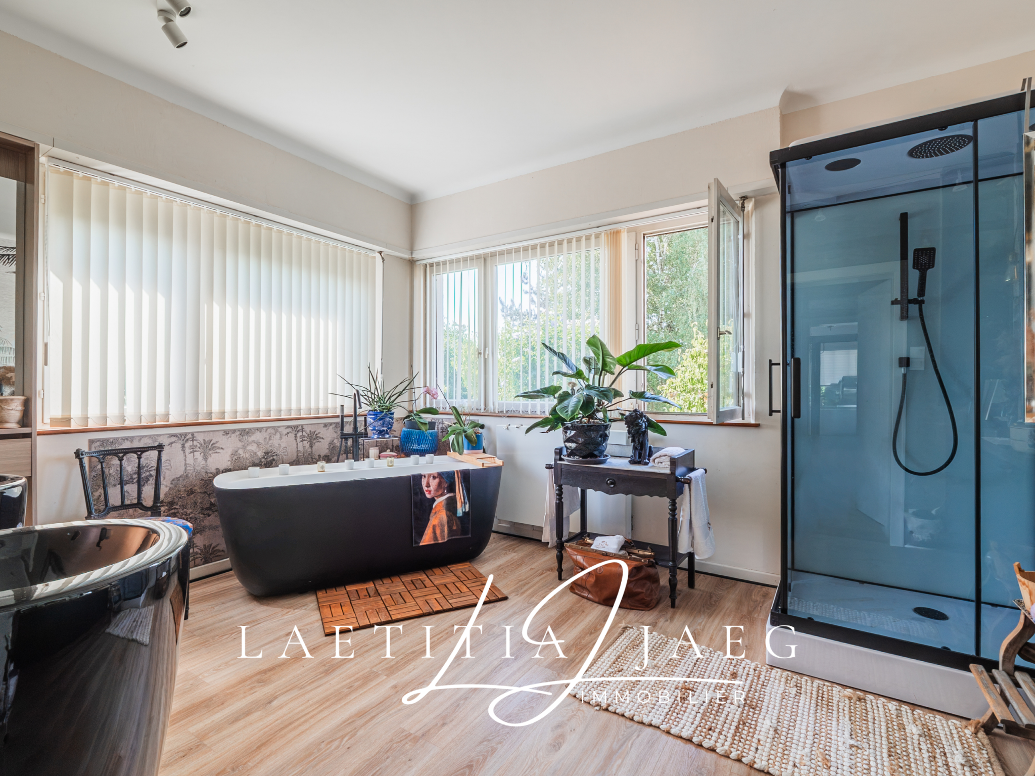 Salle de bain lumineuse avec baignoire noire et douche à l'italienne.